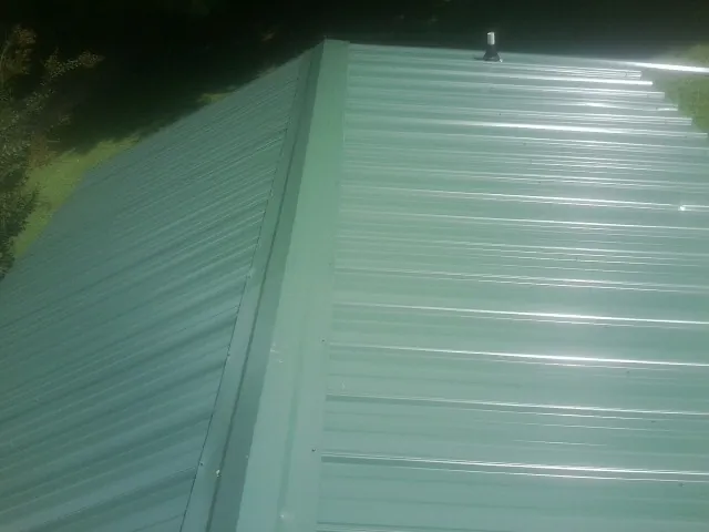 New green metal panels meeting at the ridge of a roof — Flat Roof Repair work by our crew in Allentown