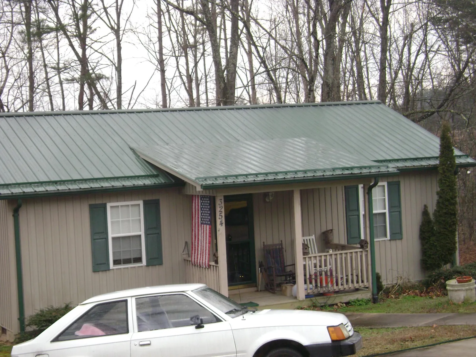 Green metal roof and front porch on a tan sided cottage in Allentown
